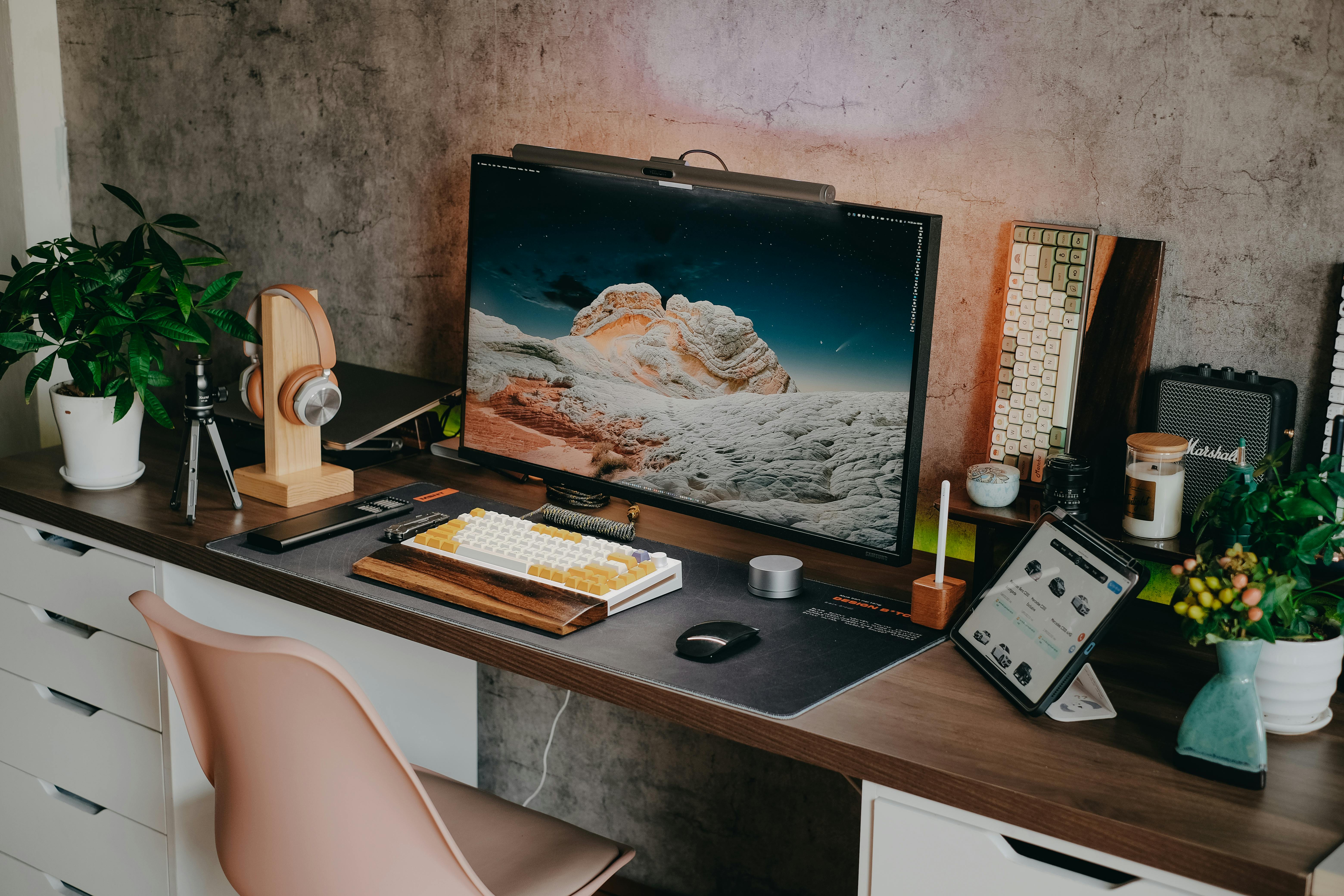 Desk setup featuring mechanical keyboard, monitor, headphones and plants